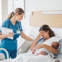 madre con su bebé en brazos llora mientras una sanitaria la consuela