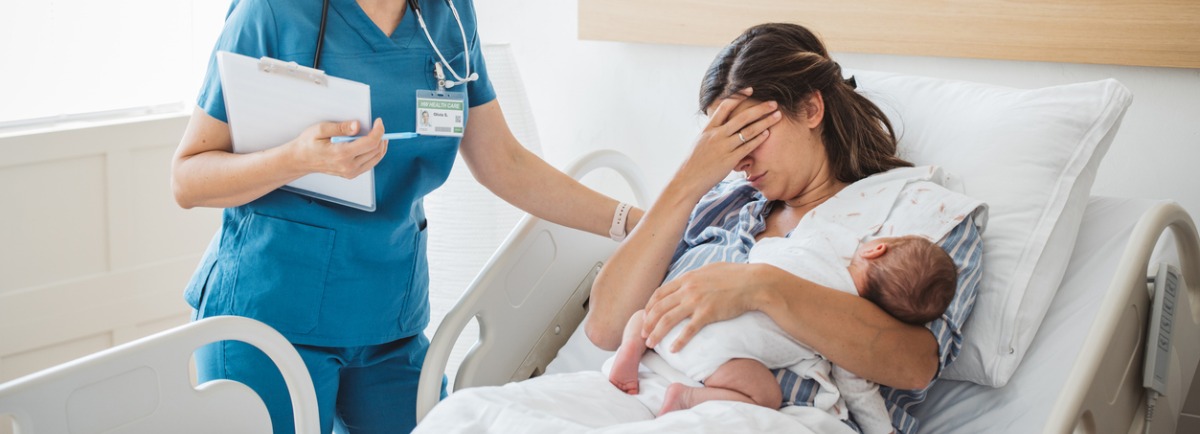 madre con su bebé en brazos llora mientras una sanitaria la consuela