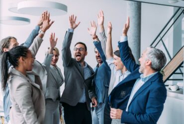 equipo de trabajadores están contentos y celebran juntos levantando los brazos