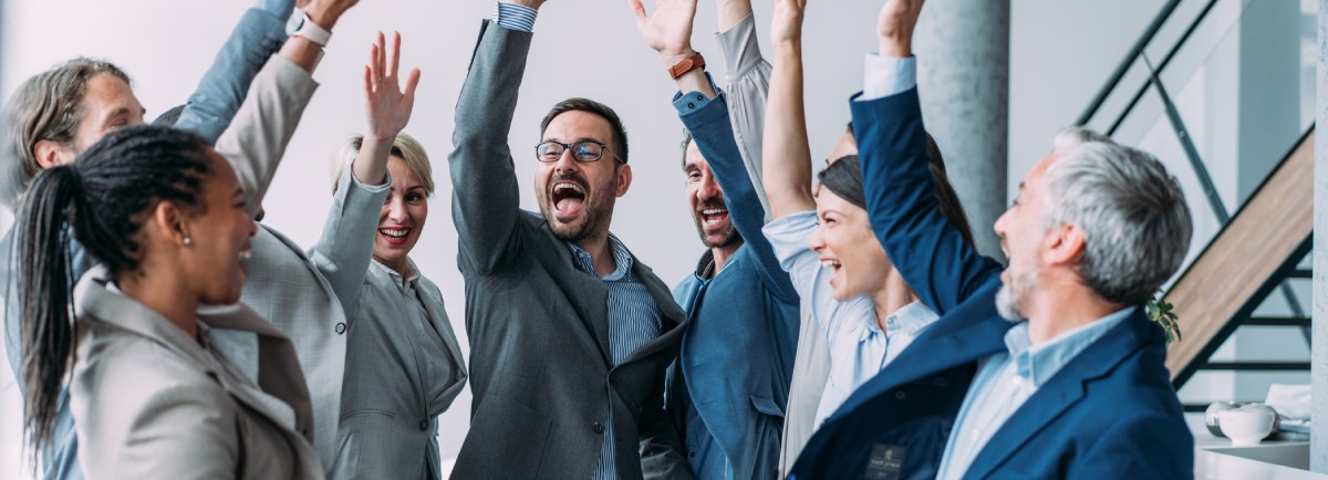 equipo de trabajadores están contentos y celebran juntos levantando los brazos