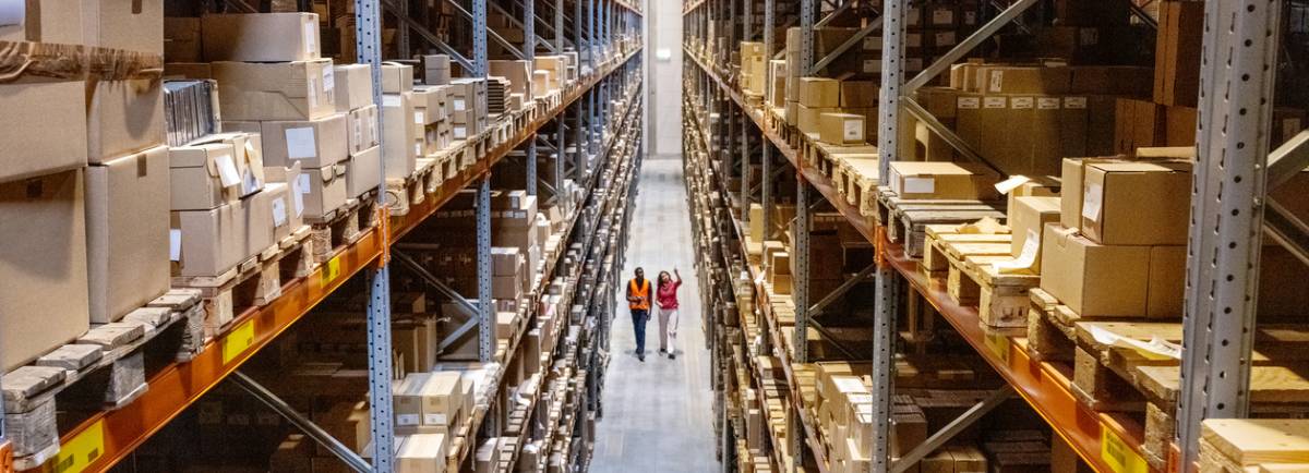 dos profesionales de la logistica caminan por un pasillo revisando el stock