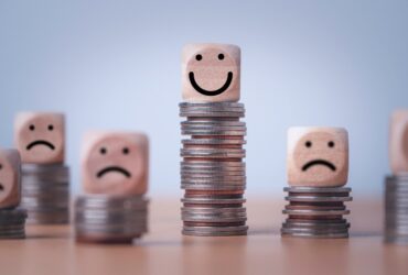 cubos de madera encima de monedas representan el salario emocional en función de la altura de las monedas y la sonrisa de los cubos