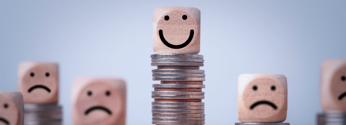 cubos de madera encima de monedas representan el salario emocional en función de la altura de las monedas y la sonrisa de los cubos